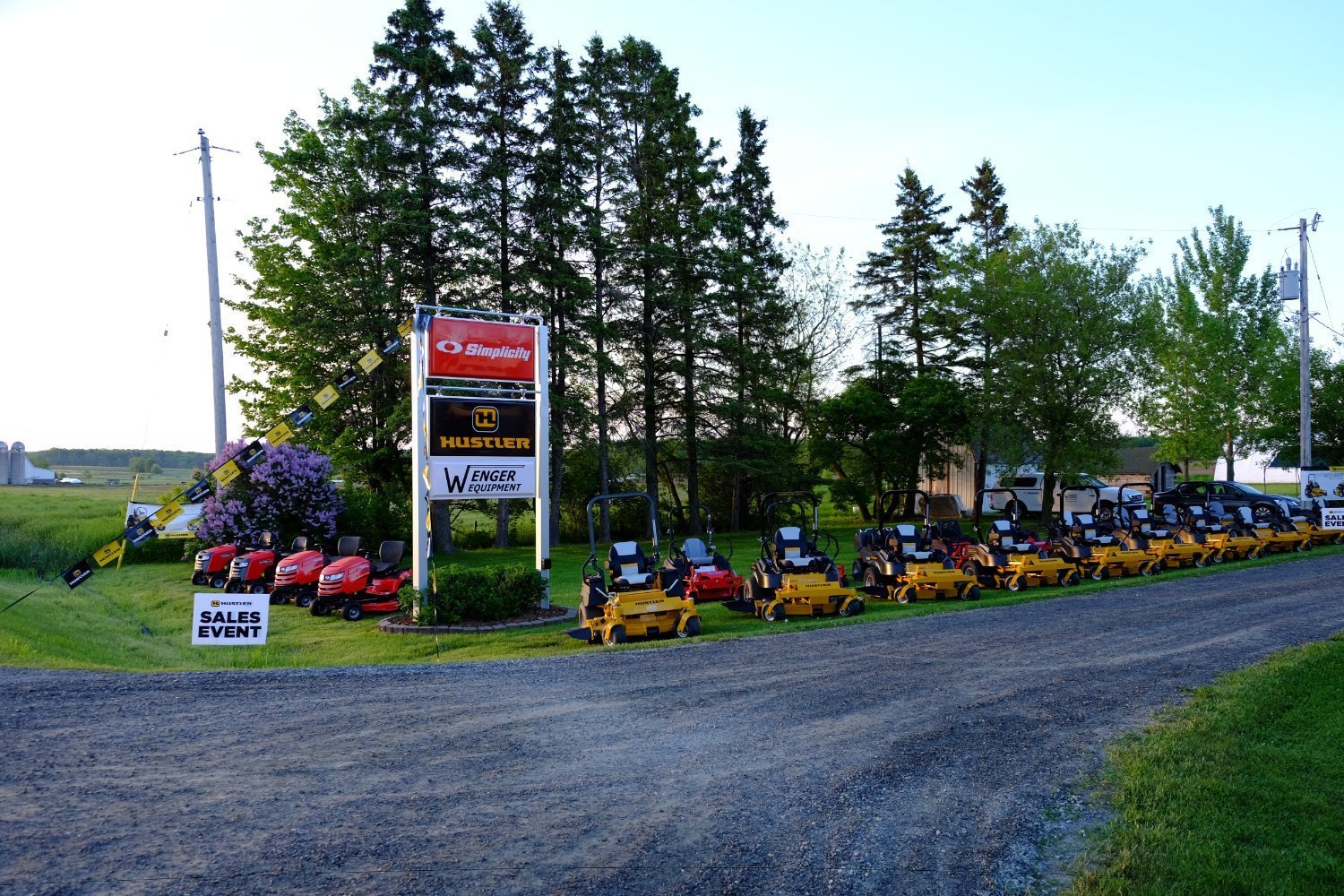 Hustler & Simplicity mowers lined up by the sign